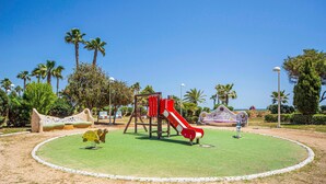 A playground with a red slide, a climbing structure, and a circular grassy area. - Gorgeous apartment in Oropesa del Mar with sauna (Oropesa del Mar)