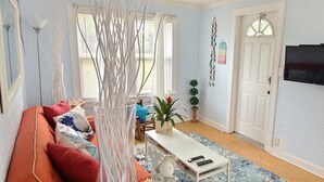 A living room with a sofa, a coffee table, a TV, and a door.