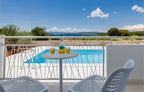 A balcony with a pool, two white chairs, and a table with drinks. - Awesome home in Punat (Punat)