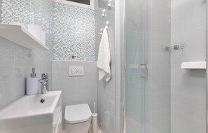 A modern bathroom with a glass shower enclosure, a white sink, and a toilet. - Awesome home in Punat (Punat)