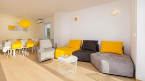 A modern living room with a sofa set, a dining table with chairs, and a round coffee table. - Awesome home in Punat (Punat)