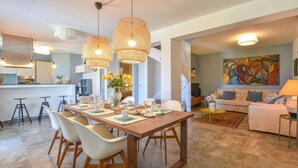 Un espace repas moderne avec une table en bois, des chaises blanches et un vase rempli de fleurs jaunes.