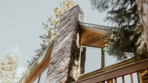 Un balcone in legno con un camino in pietra, un portone di garage e un cartello di benvenuto.