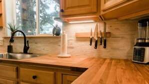 Una cucina con mobili in legno, un lavello in acciaio inossidabile, un portaserviti e un frullatore.
