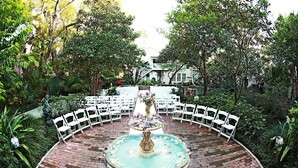 A circular outdoor seating area with white chairs arranged around a central fountain. - Courtyard at Lake Lucerne (Orlando)