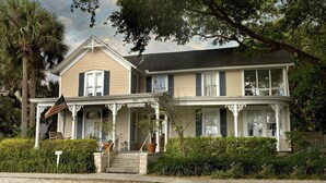 A two-story house with a porch, a flag, and a sign indicating a restaurant. - Courtyard at Lake Lucerne (Orlando)