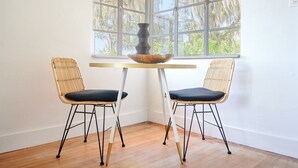 A room with two wicker chairs, a small round table, and a large window with a view of trees. - Courtyard at Lake Lucerne (Orlando)