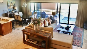 Ein modernes Hotelzimmer mit Essbereich, einer Sofagarnitur, einem Couchtisch und Blick auf die Außenterrasse.