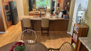 Una cocina moderna con armarios de madera, encimera de granito y un comedor con mesa redonda y sillas.
