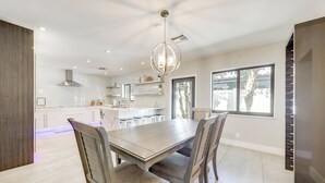 Une cuisine moderne avec une grande table à manger, des chaises en bois et des luminaires suspendus.