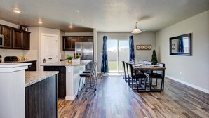 A modern kitchen with dark wood cabinets, a stainless steel refrigerator, and a granite countertop. - South Nampa Family Home | Cali King | Game Loft | 5 TVs | Near Downtown Nampa (Nampa)