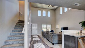A spacious living area with a staircase, a sofa, and a kitchen area. - South Nampa Family Home | Cali King | Game Loft | 5 TVs | Near Downtown Nampa (Nampa)