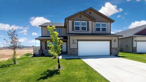 A two-story house with a garage, a well-maintained lawn, and a small tree in the front yard. - South Nampa Family Home | Cali King | Game Loft | 5 TVs | Near Downtown Nampa (Nampa)