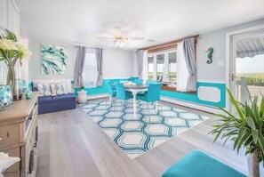 A modern living room with a sofa, a dining table with chairs, and a view of the outdoors. - Private Dock, Private Pool & Bayfront Paradise (Middle Township)