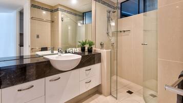 Un baño moderno con un lavamanos grande, cabina de ducha de vidrio y una puerta de vidrio que da a la ducha.