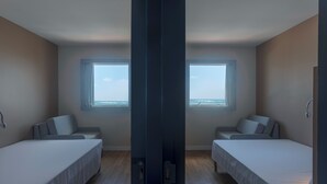 Quarto com duas camas, uma janela grande e vista para o oceano.