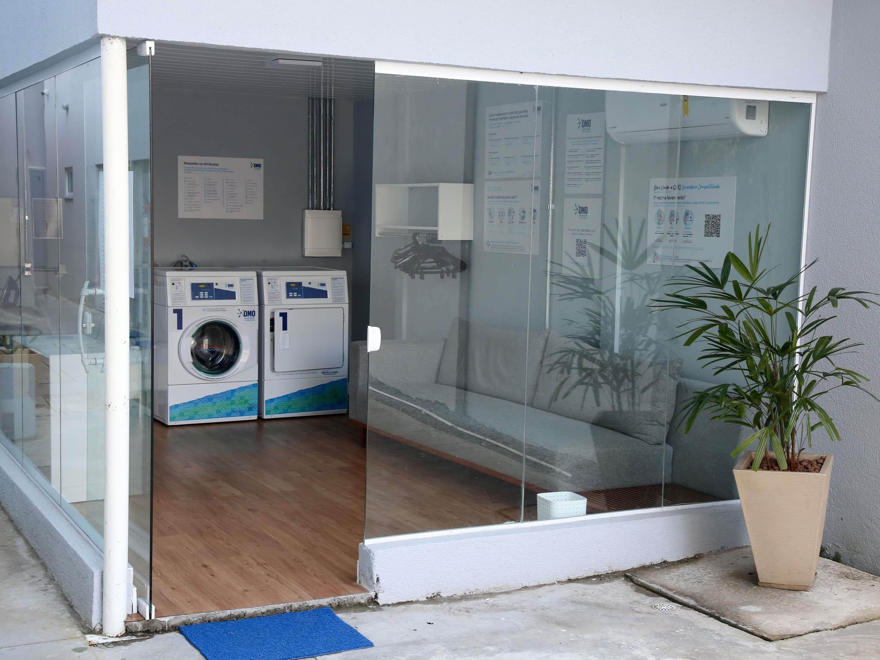 Une buanderie équipée de deux machines à laver, d’un tapis bleu et d’une plante en pot.