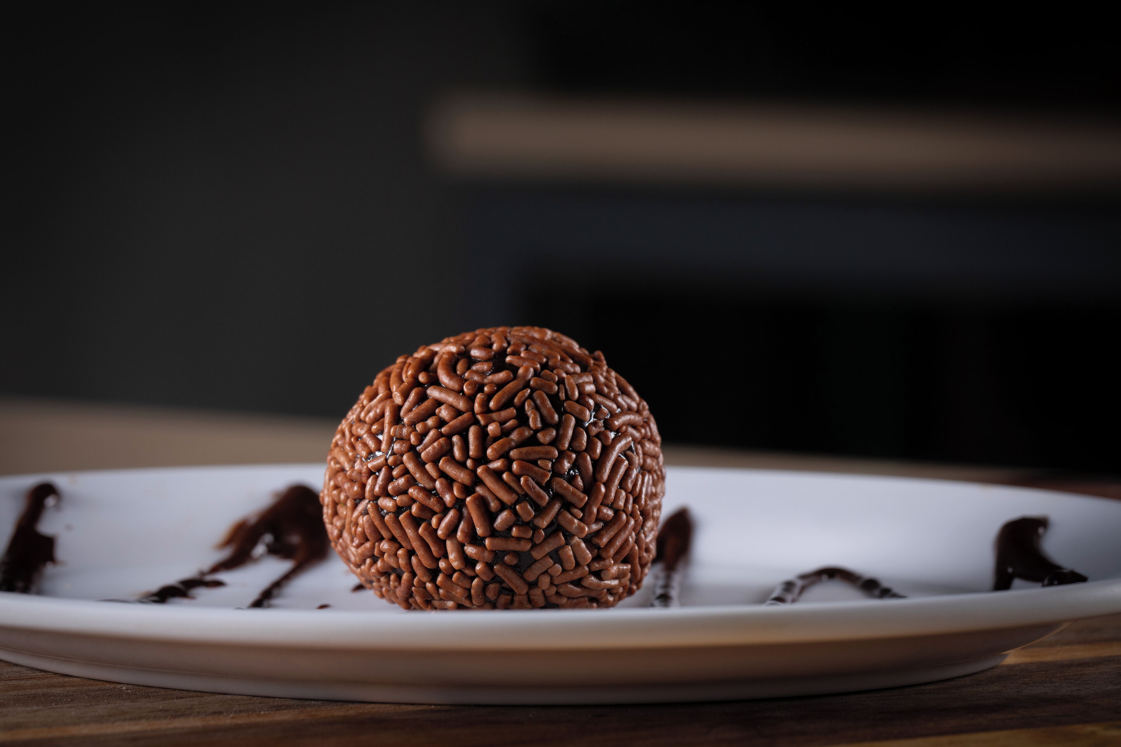 A chocolate truffle on a white plate with chocolate sauce.