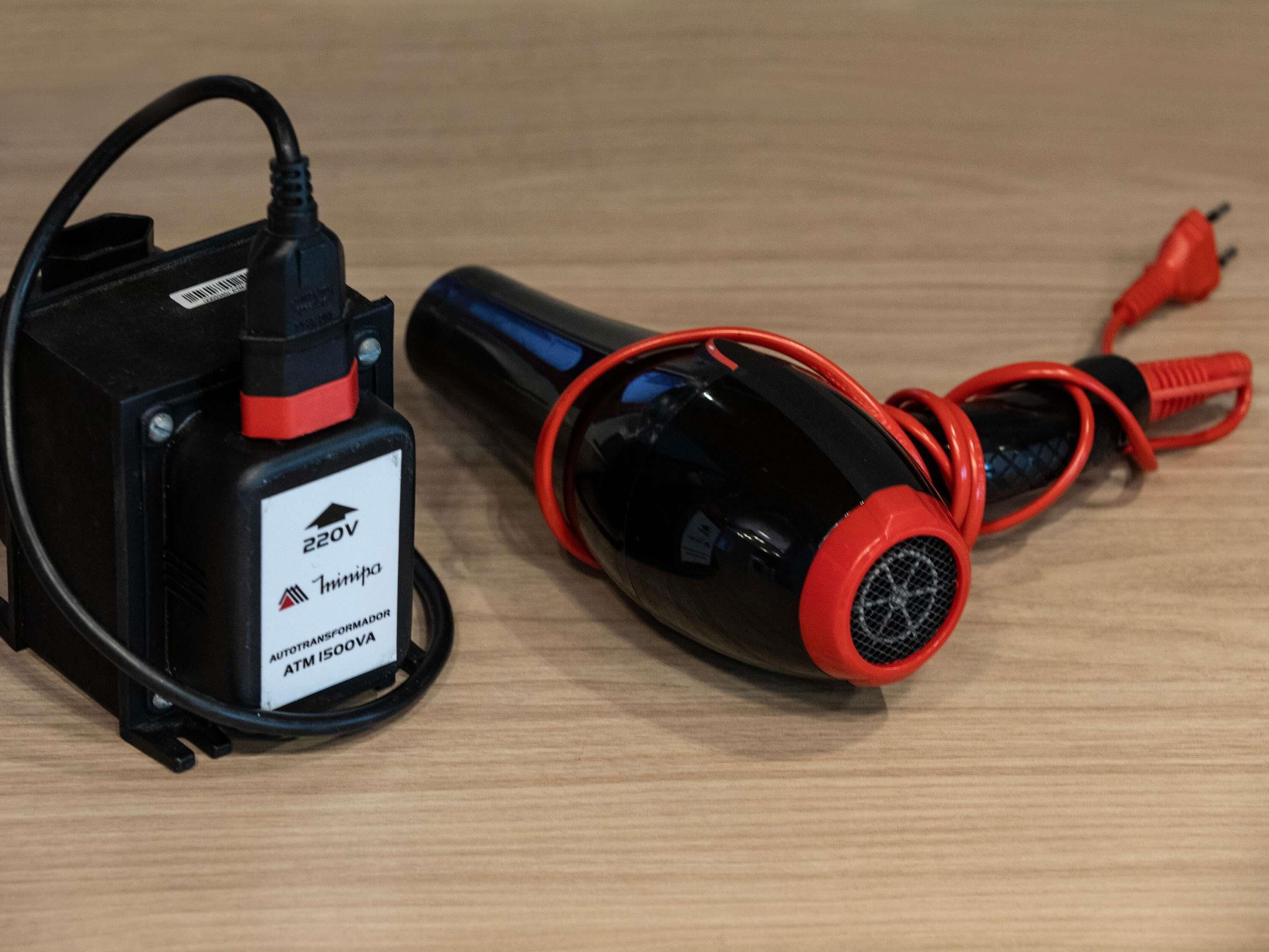 A black and red power adapter with a label indicating 220V and 1500VA, and a cylindrical device with a red and black cord.