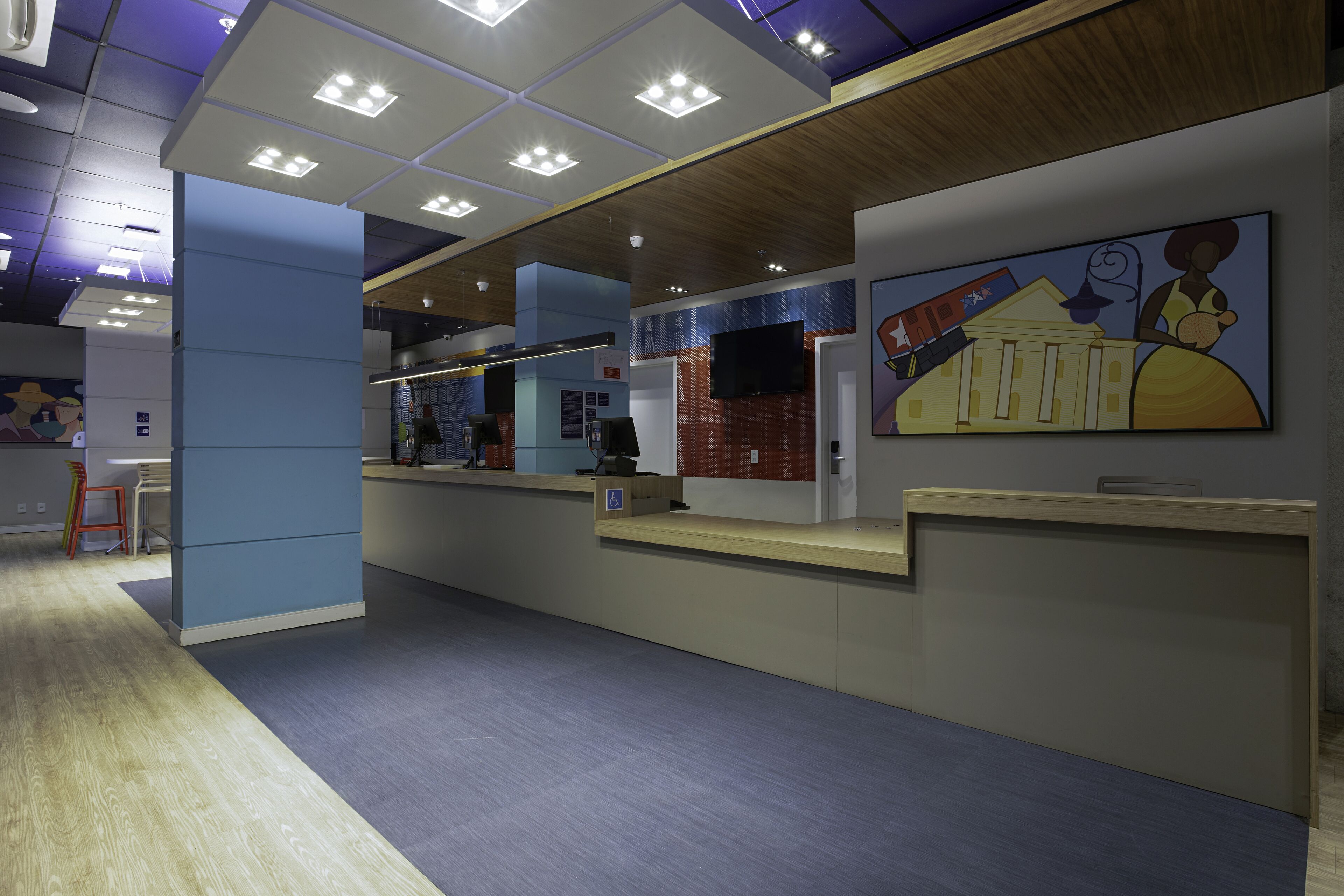 A reception area with a counter, a mounted television, and a painting on the wall.