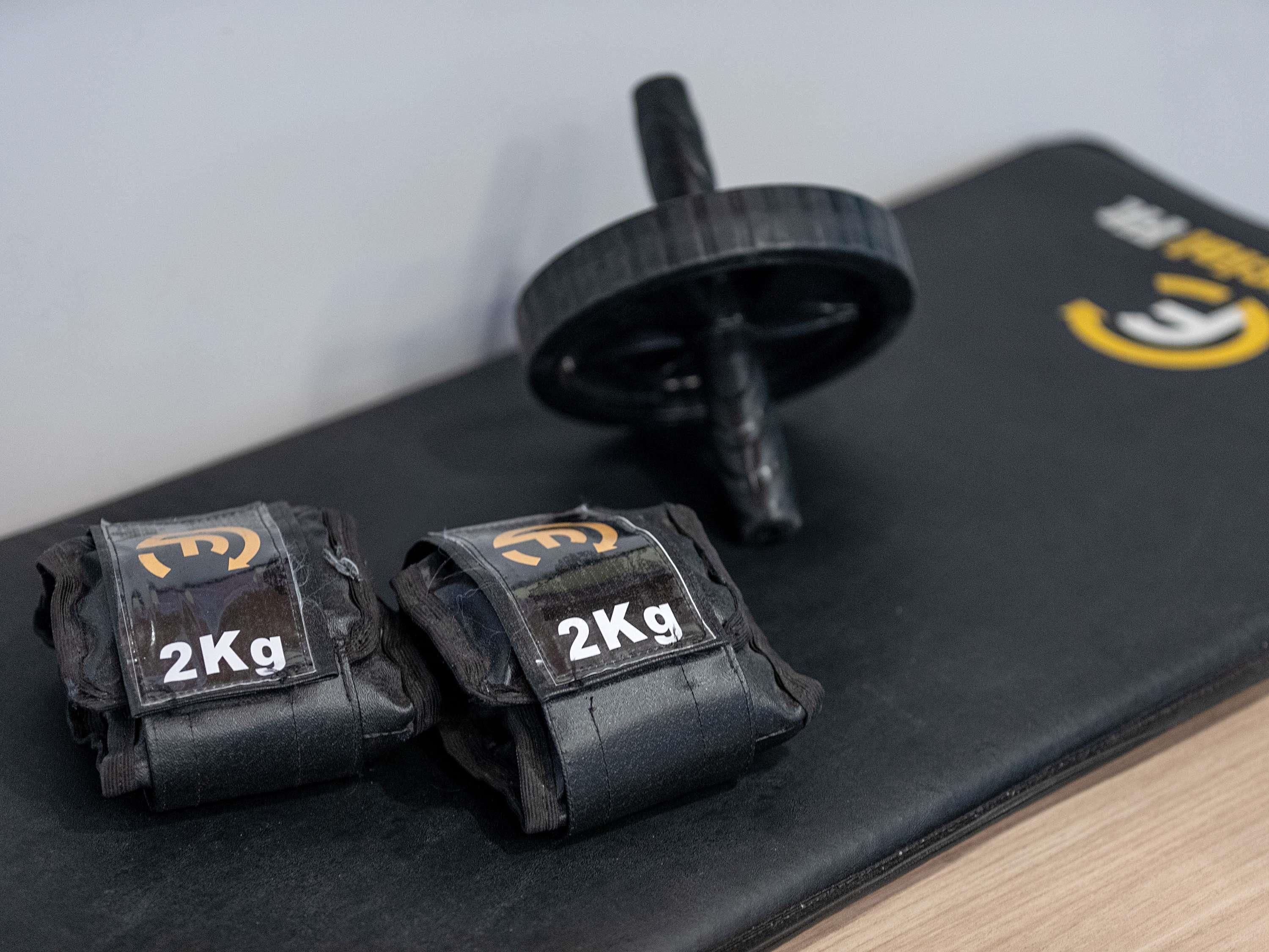 Two weightlifting straps with '2Kg' labels on a black mat.