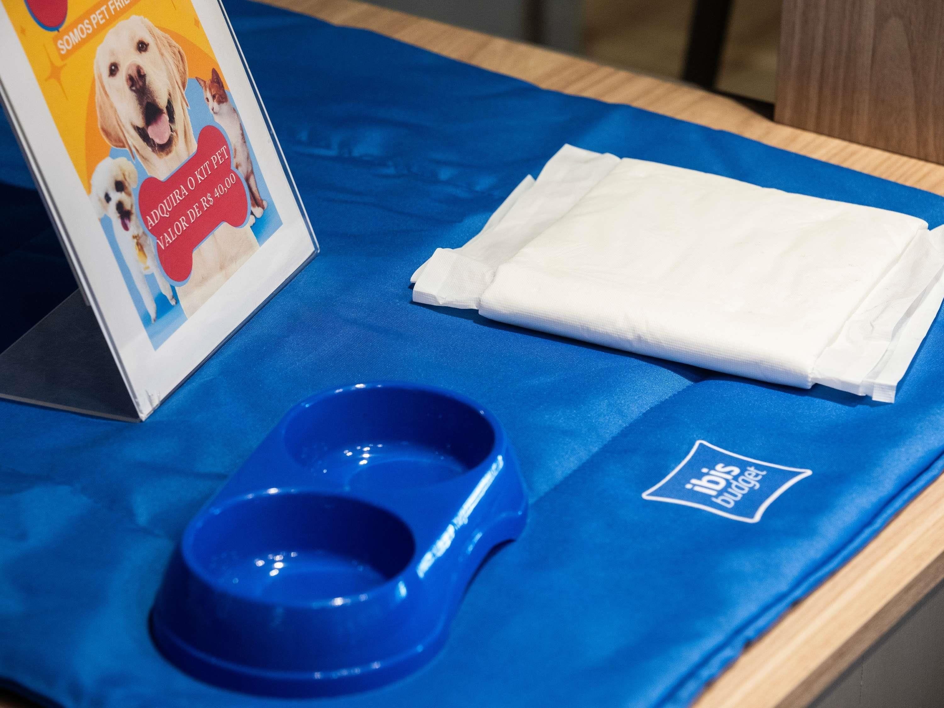 A blue table with a dog bowl, a folded white cloth, and a sign with pet services.