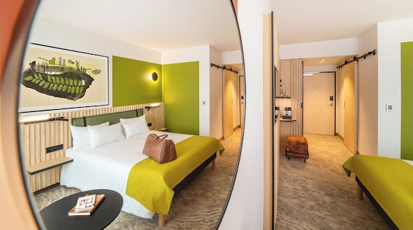Una habitación de hotel con cama, mesita de noche y un pequeño rincón de descanso.