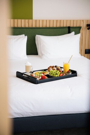 A bed with a tray of breakfast items including coffee, croissants, fruit, and juice.