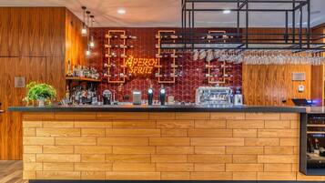 A modern bar area with a wooden counter, a neon sign, and a variety of bottles and glasses.