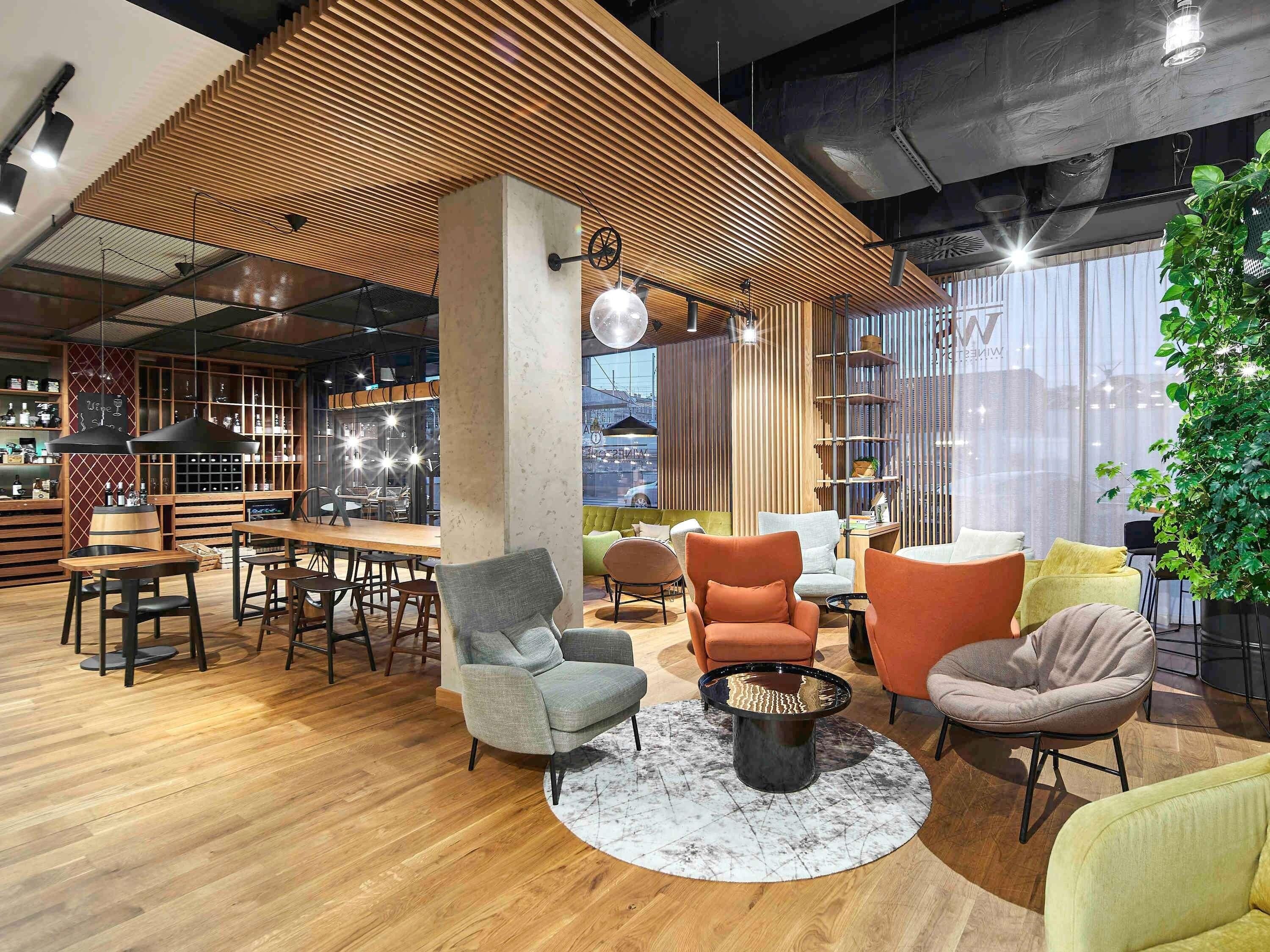 Un interior moderno con techo de madera, una zona de bar, asientos con una mesa de centro redonda y un ventanal con vistas.