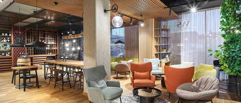 Un interior moderno con techo de madera, una zona de bar, asientos con una mesa de centro redonda y un ventanal con vistas.