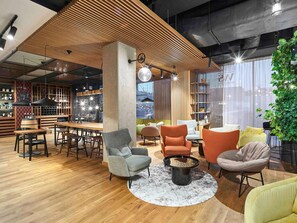 A modern interior with a wooden ceiling, a bar area, seating with a round coffee table, and a large window with a view.