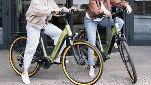Dos personas montando en bicicleta frente a un edificio con la leyenda 'MERCURE HOTEL'.
