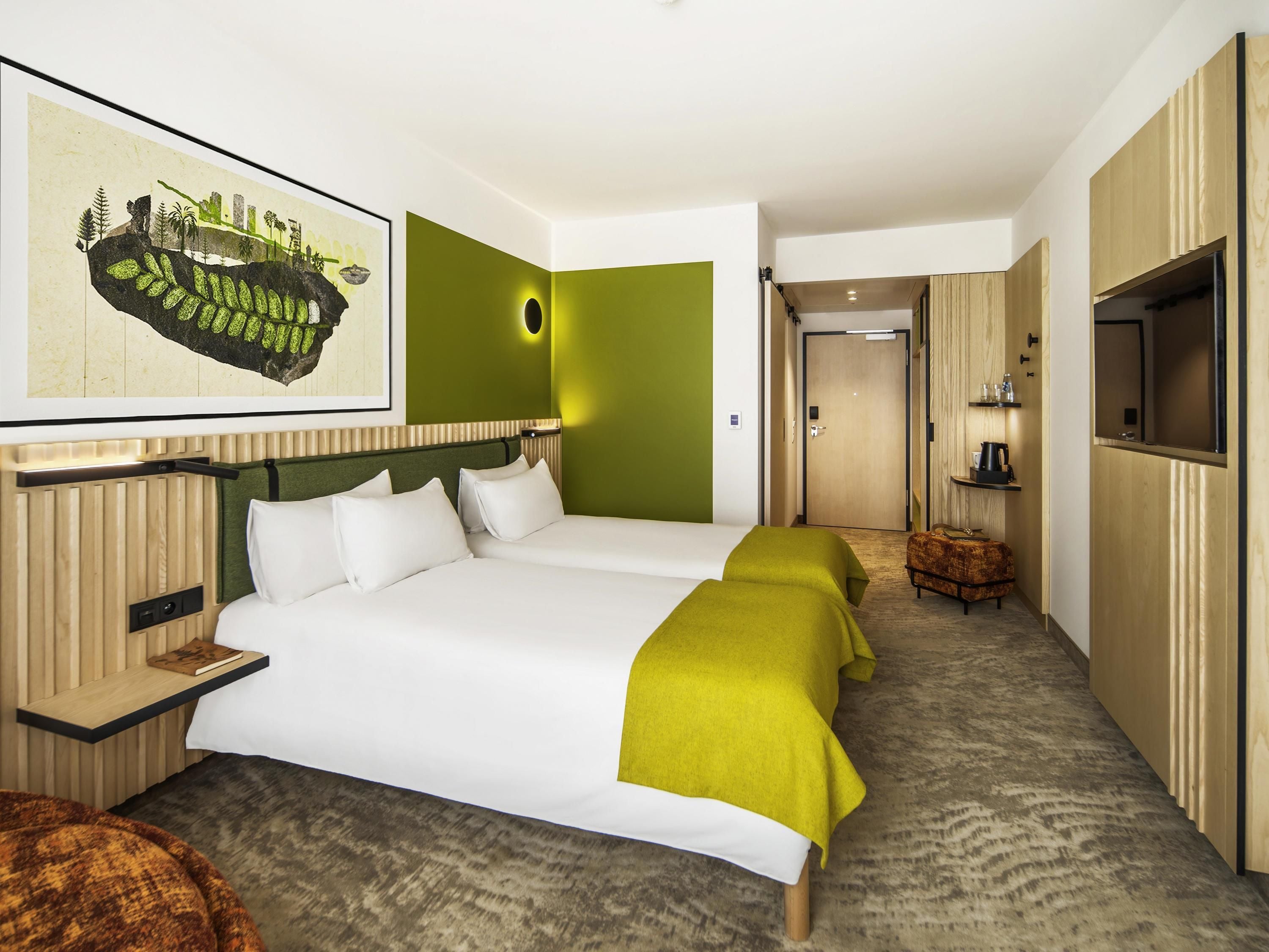 Una camera d'albergo con un letto grande, una TV, un piccolo angolo salotto e una porta che dà su un corridoio.