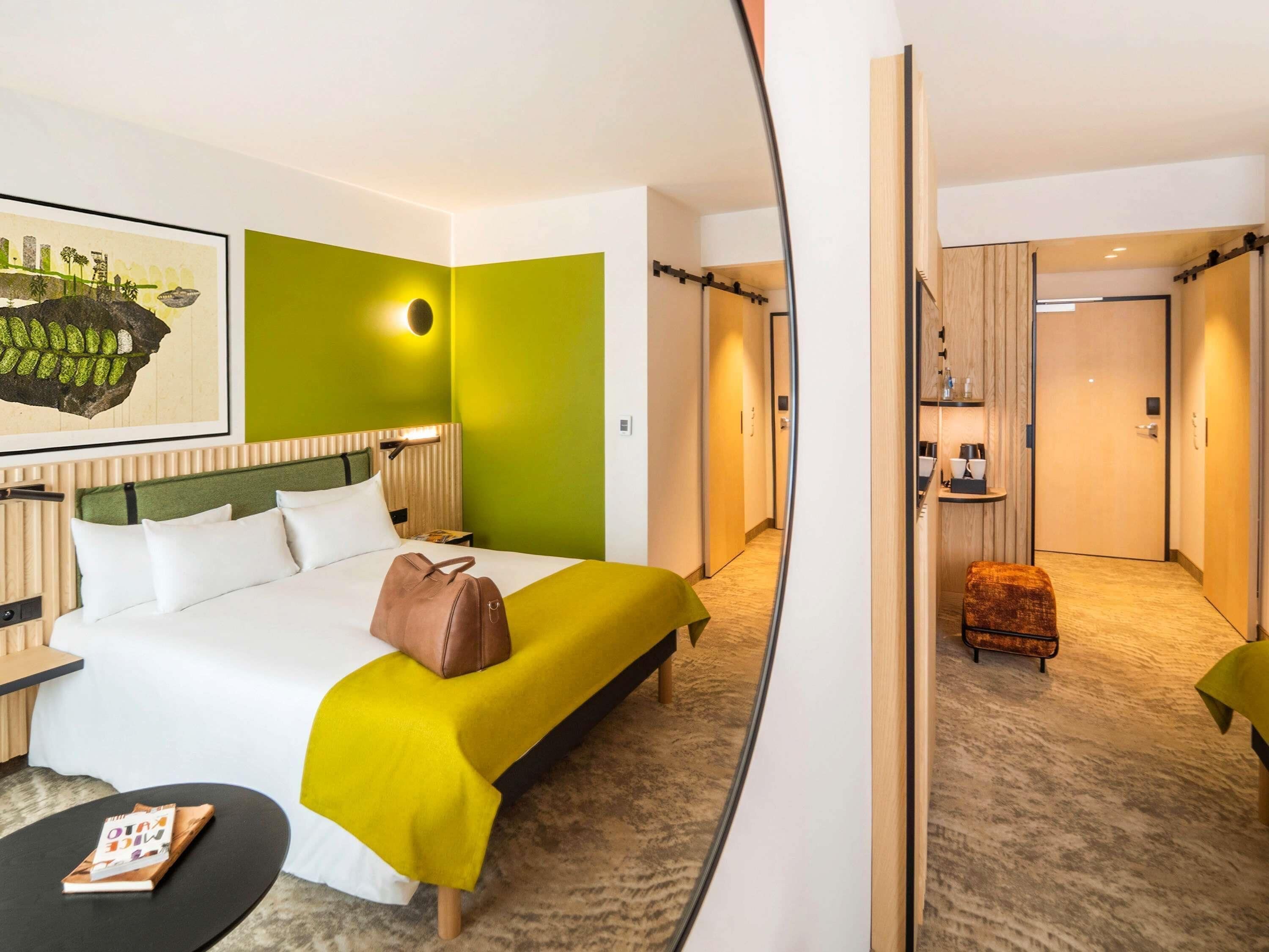 Une chambre d’hôtel avec un lit, une table de chevet et une petite table sur laquelle se trouve un livre.