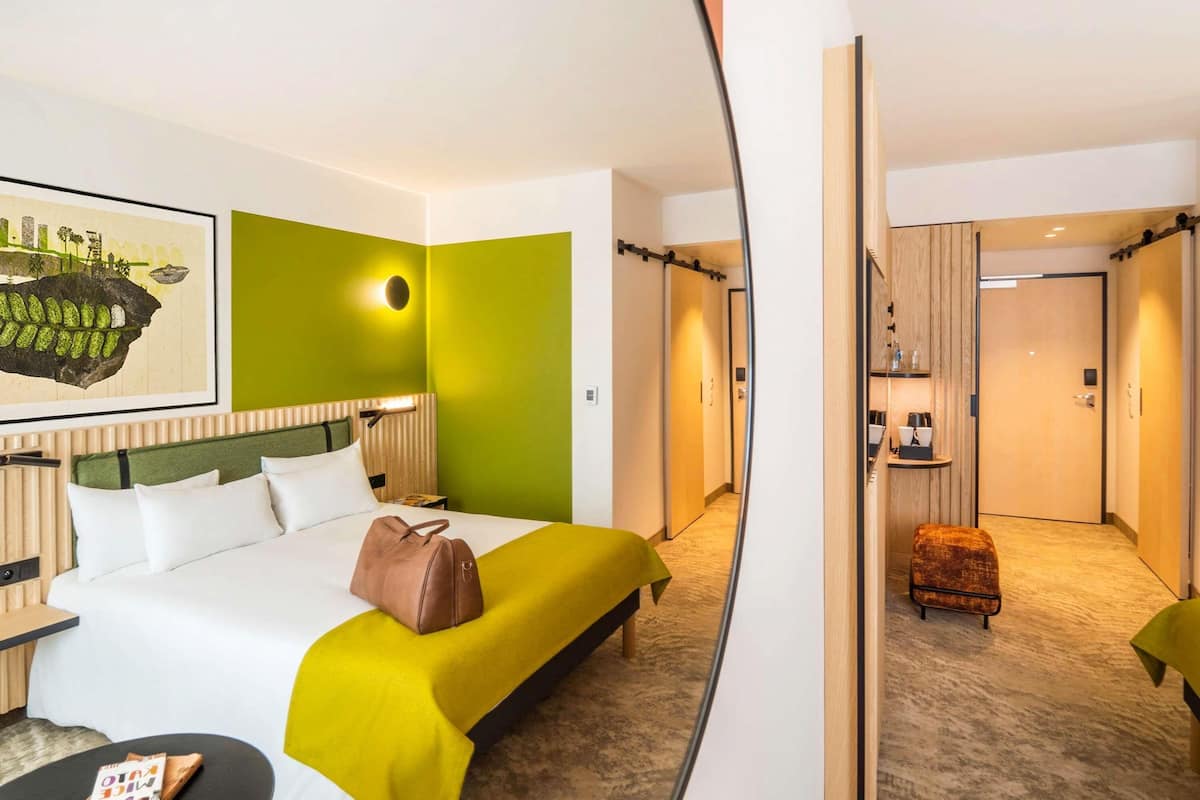 Une chambre dâhĂŽtel avec un lit, une table de chevet et une petite table sur laquelle se trouve un livre.