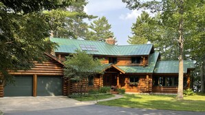 A log cabin with a green metal roof, a garage, and a well-maintained lawn. - Lakeside Lodge Vacation Rental. See discounts below for less than 12 people. (Conover)