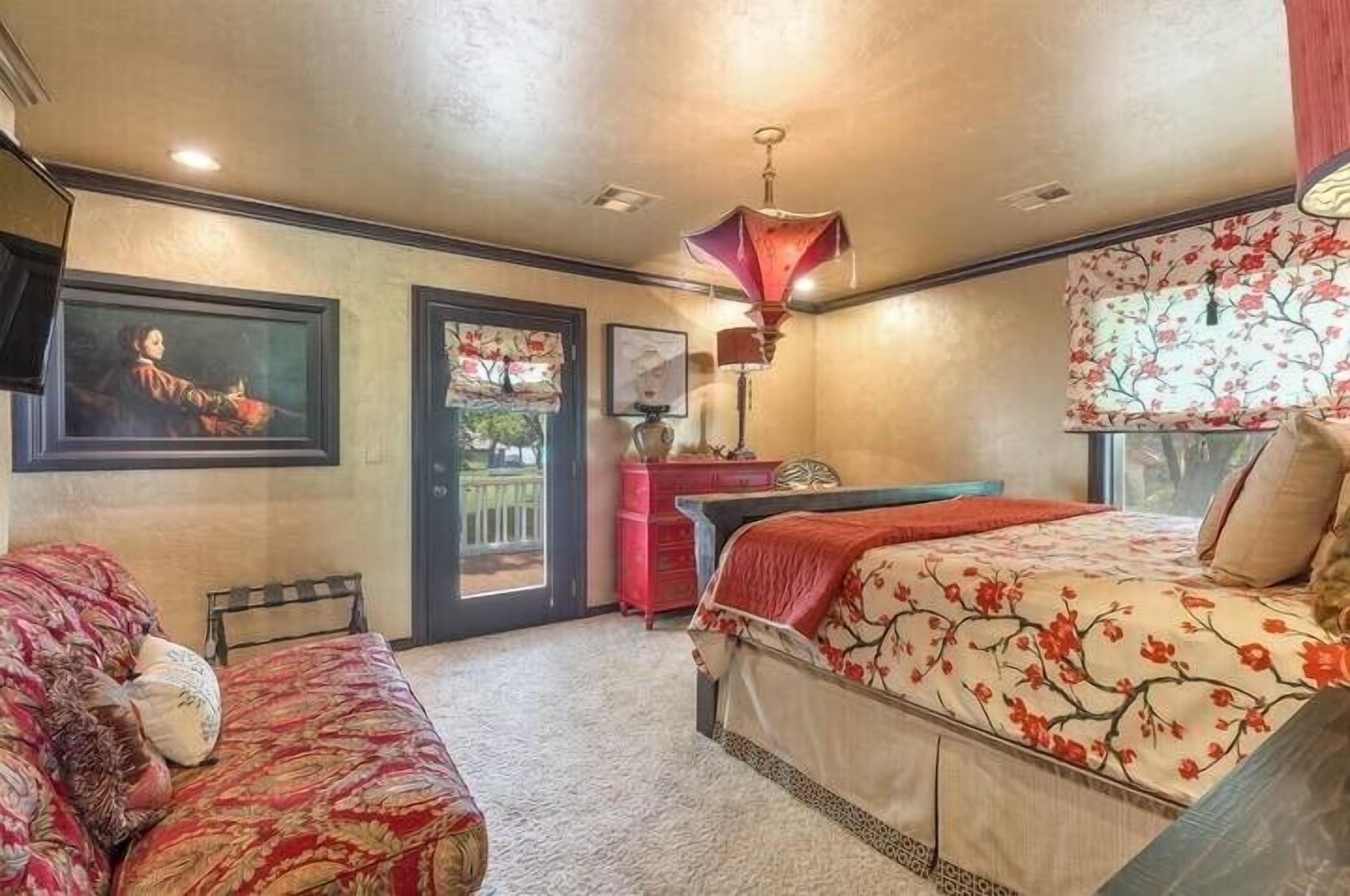 A bedroom with a bed, a desk, and a chair. There is a door leading to a balcony.