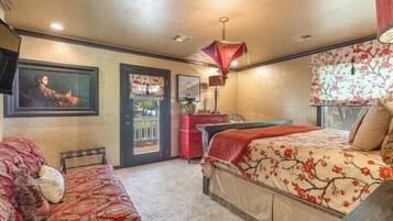 A bedroom with a bed, a desk, and a chair. There is a door leading to a balcony.