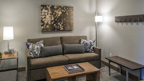 Una sala de estar con sofá, una mesa de centro, lámpara y estante de pared.