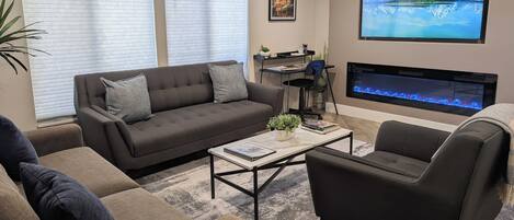 Un salon comprenant un canapé, des fauteuils, une table basse et une cheminée.