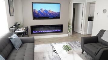Una sala de estar moderna con chimenea, un televisor de pantalla plana montado encima y un sofá.