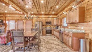 A log cabin interior with a dining area, kitchen, and a fireplace. - *Soaring Eagle* VIEWS! Heated POOL-Theater-Game Rm (Sevierville)