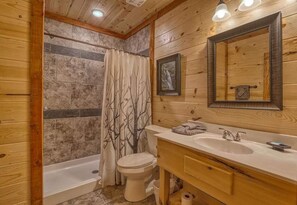 Un baño de cabaña de madera con bañera, inodoro y tocador.
