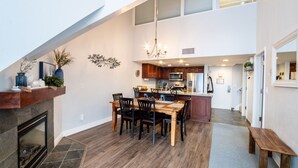 A spacious kitchen with a dining area, a fireplace, and a chandelier.