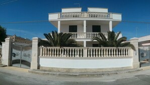 Un edificio a più piani con facciata bianca, un balcone al piano superiore e un ingresso carrabile.