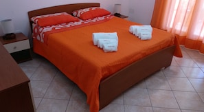 Un lit avec une couvre-lit orange, deux oreillers et un ensemble de serviettes posées sur le lit.