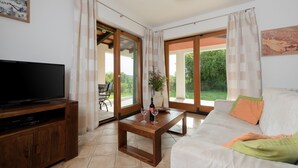 A living room with a television, wooden coffee table, and a sofa with cushions. - Villa Athos 2 With two Apartments, Pool and Garden (Labin)
