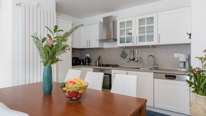 A modern kitchen with white cabinets, a stainless steel range hood, and a coffee maker. - Villa Athos 2 With two Apartments, Pool and Garden (Labin)