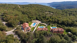 A hillside property with multiple buildings, a swimming pool, and a view of the sea. - Villa Athos 2 With two Apartments, Pool and Garden (Labin)